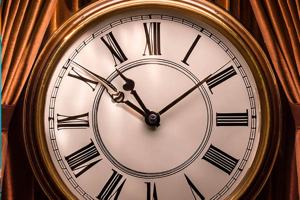 Eine nostalgische große goldene Uhr. Im Hintergrund ein schwerer Vorhang.